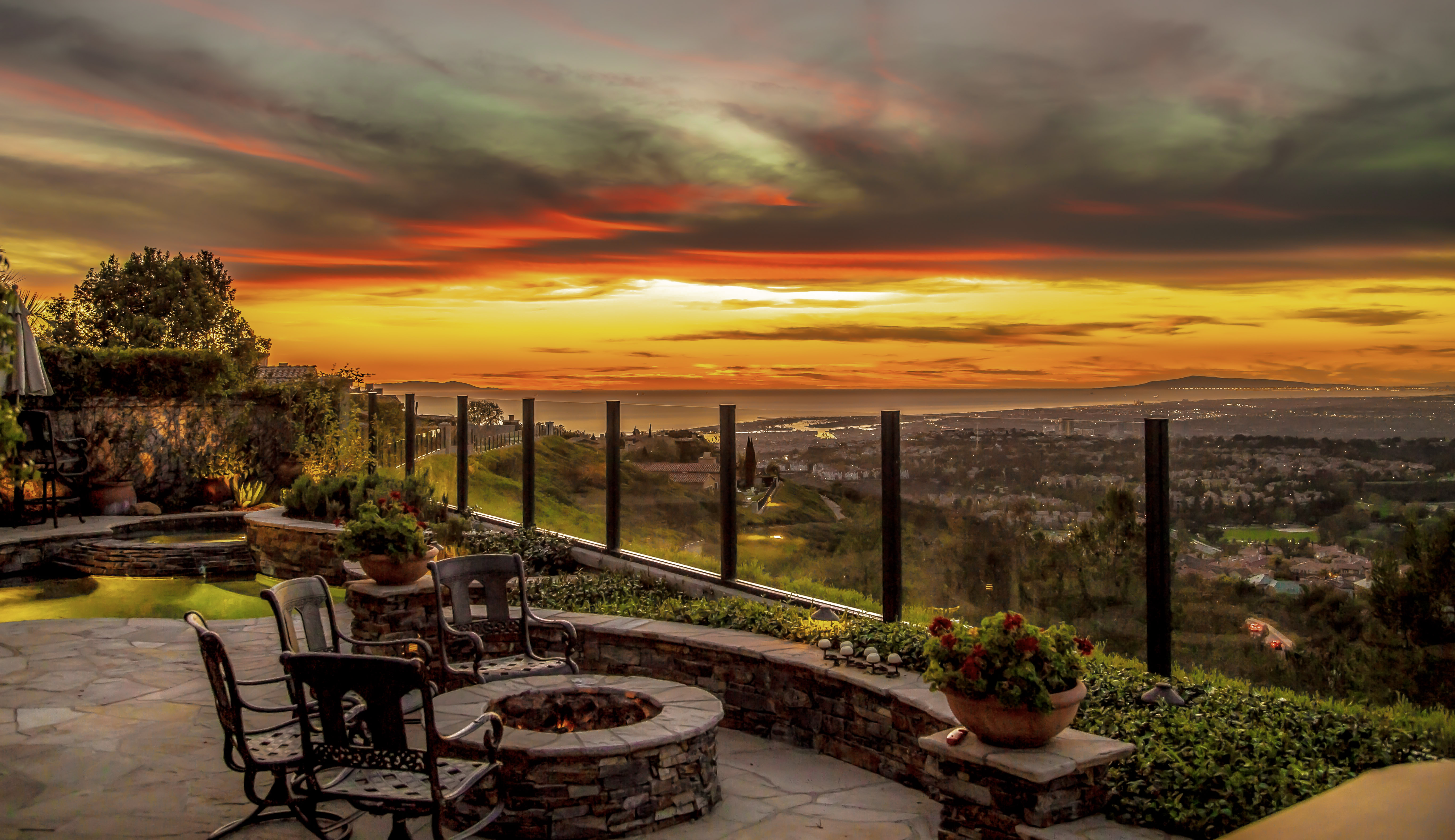Sunset view from a stone patio with a fire pit overlooking a coastal valley and the ocean