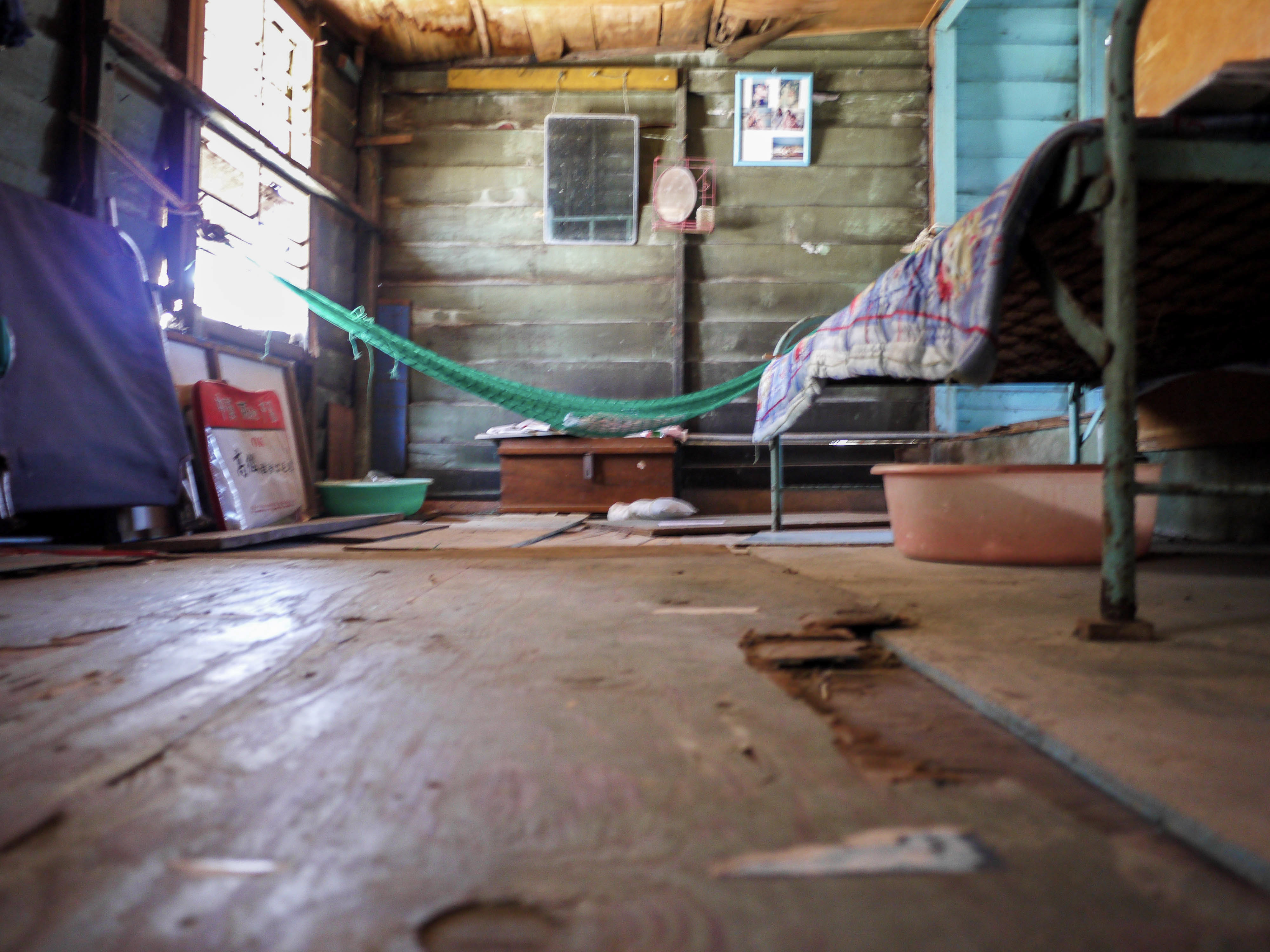 Green hammock and metal bed in a wooden room with daylight from the side